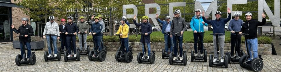 Gruppe auf Segway-Tour in Bremen vor dem Schriftzug BREMEN – Teilnehmer mit Helmen auf ihren Segways