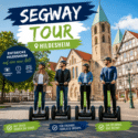 Vier Personen fahren mit Segways durch die historische Altstadt von Hildesheim vor Fachwerkhäusern und Kirche
